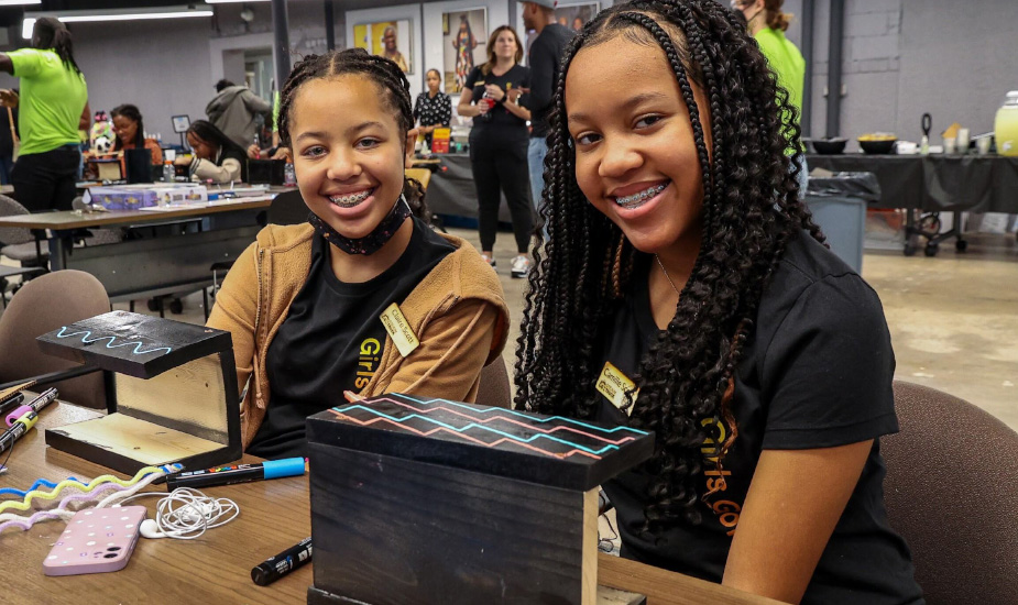 Two girls proudly admire their completed robot project